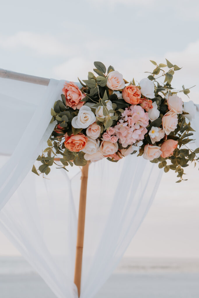 Floral arch with white fabric and roses.