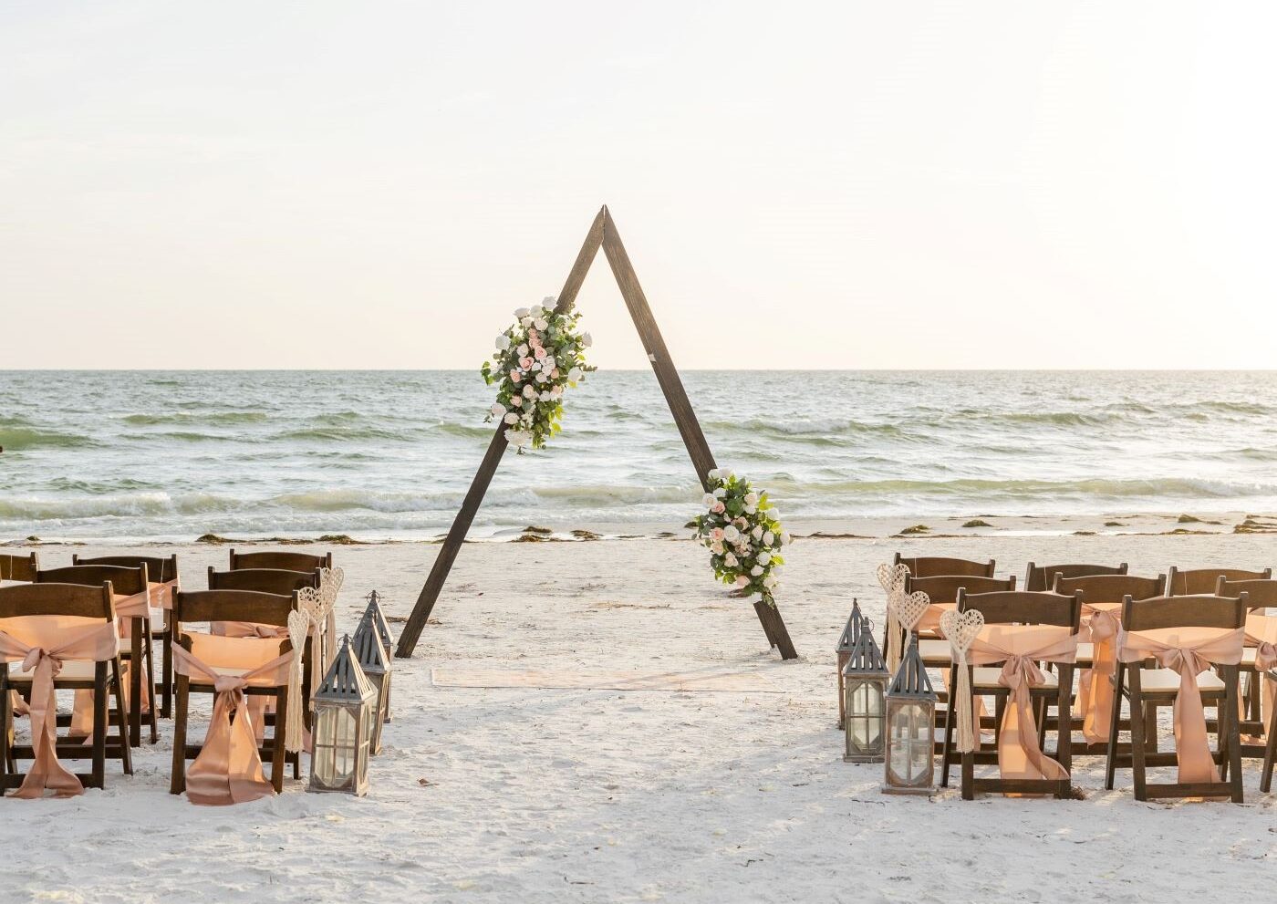 Beach wedding ceremony with floral arch.