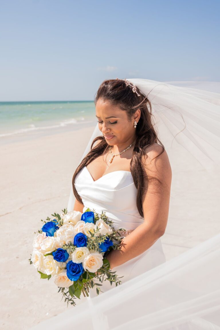 Bride in white dress holding blue roses.